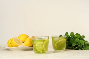 Nane aromalı lezzetli limonata ve beyaz arka planda limonlar.