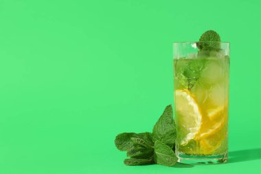Yeşil arka planda naneli bir bardak lezzetli limonata.