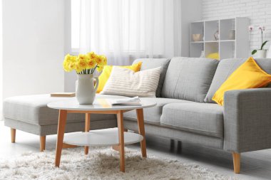 Oturma odasındaki kahve masasındaki sürahide nergis çiçeği