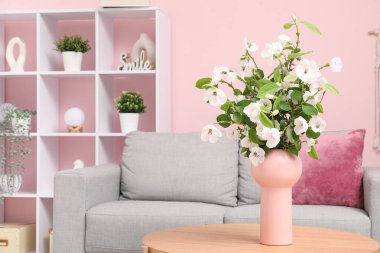 Rahat kanepesi, sehpası ve çiçek açan ağaç dalları olan şık bir oturma odası.