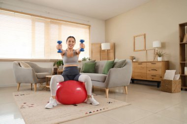 Spor yapan, halterli, spor ayakkabılı bir Asyalı kadın.