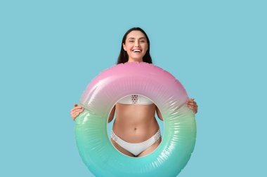 Mavi arka planda şişme yüzüklü, güzel genç bir kadın.