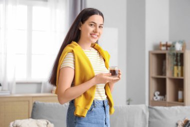 Evinde bir fincan sıcak kahveyle güzel genç bir bayan.