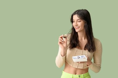 Yeşil arka planda bir kutu lezzetli çikolata şekeri olan genç bir kadın.