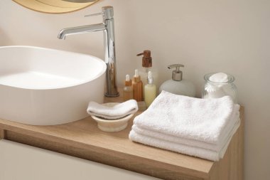 Temiz havlu yığını, kozmetik ürünler şişeleri ve ahşap çekmecelere batmak.