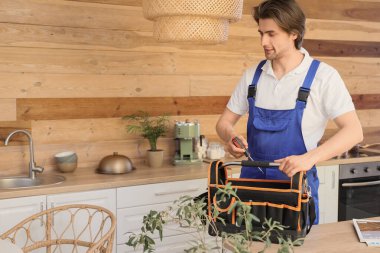 Mutfakta alet çantası olan bir erkek tamirci.