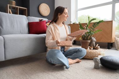 Sadhu tahtası olan genç bir kadın evdeki halıda oturuyor.