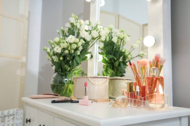 Dekoratif kozmetik ürünleri ve vazo. Soyunma odasındaki masada çiçekler.