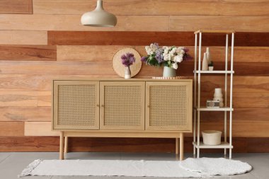 Odanın ahşap duvarının yanında şık bir dolap ve raf var.