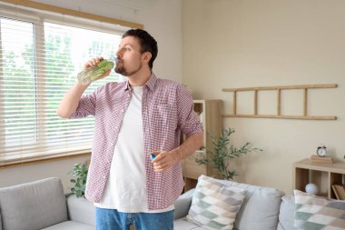 Genç adam evde salatalık suyu içiyor.