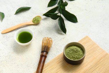 Beyaz arka planda chasen ile bir kase kibrit çayı ve pudra.