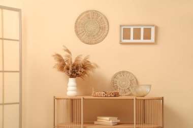 Bej duvarın yanında farklı dekorları olan ahşap raf ünitesi.