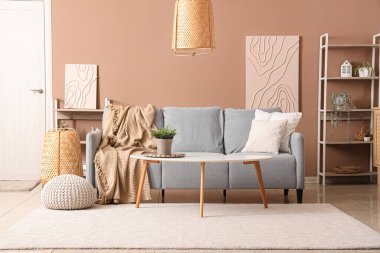 Gri kanepesi ve bej duvarın yanında kahve masası olan şık bir oturma odası.