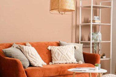 Kahverengi kanepesi ve bej duvarın yanında kahve masası olan şık bir oturma odası.