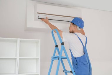 Merdivendeki erkek müteahhit odaya klima kuruyor.