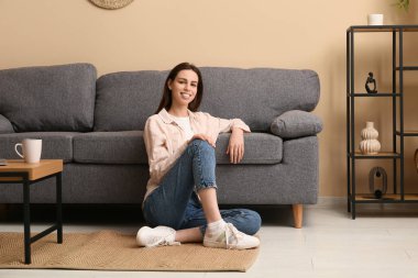 Şık bir oturma odasında, kanepenin yanında oturan genç bir kadın.