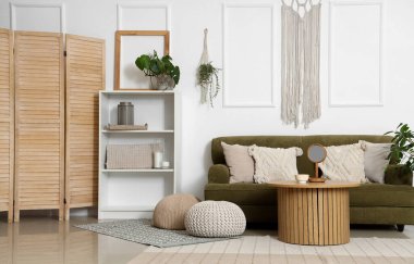 Interior of light living room with green sofa and wall tapestry