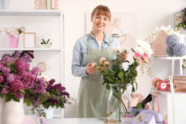 Stüdyoda elinde çiçek vazosu olan kadın çiçekçi.