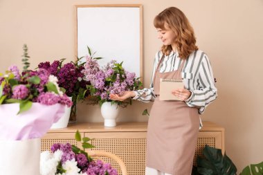 Çiçekçide çalışan defterli bir kadın çiçekçi.