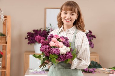 Çiçekçide elinde leylaklarla güzel bir buket tutan kadın çiçekçi.