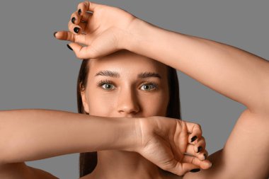 Gri arka planda güzel kaşları olan genç bir kadın.