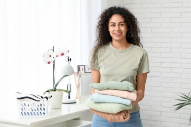 Güzel bir Afro-Amerikalı kadın evde temiz giysiler giyiyor.