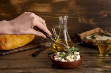 Çatallı kadın eli ve bir kase lezzetli peynir ve ahşap arka planda biberiye.