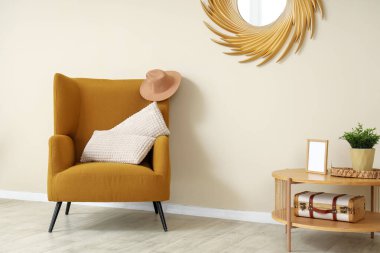 Rahat koltuğu, yastıkları, sehpası ve aynası olan minimalist bir oturma odası.