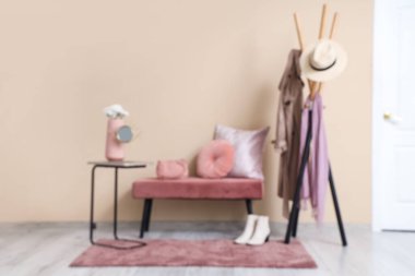 Sade bank, elbise askısı ve bej duvarın yanında halı, bulanık manzara.