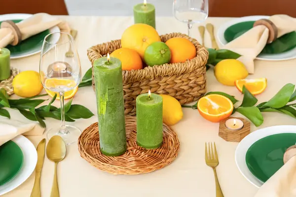 Oturma odasında turunçgil meyveleri, yanan mumlar ve beyaz masa örtüsü olan güzel bir masa.