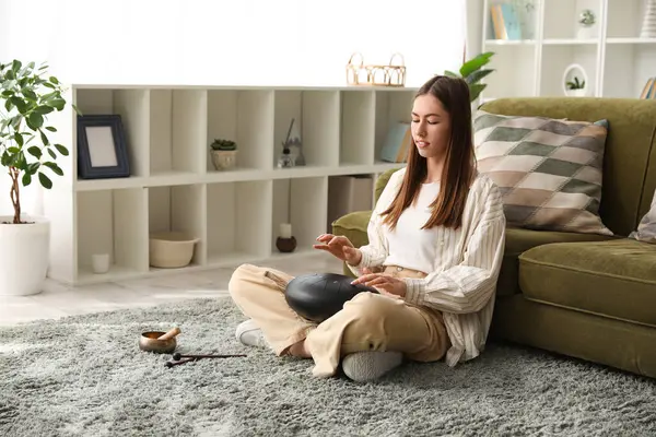 Evde halıda glukofon çalan genç bir kadın.