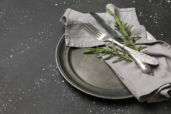 Siyah grunge arkaplan üzerinde peçete, çatal bıçak ve biberiye ile şık masa ayarları