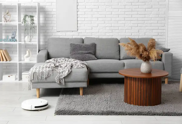 Interior of modern living room with robot vacuum cleaner on floor