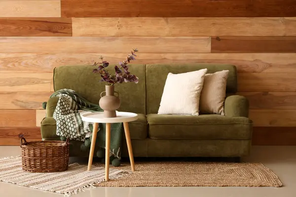 Oturma odasının içinde kanepe, masa ve vazoda yapay okaliptüs var.