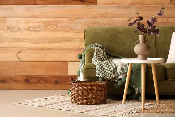 Oturma odasının içinde kanepe, masa ve vazoda yapay okaliptüs var.