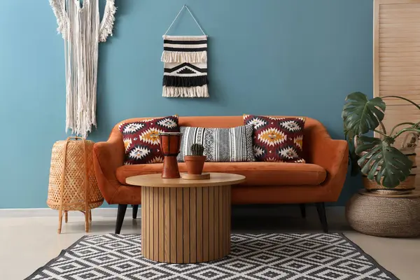 Interior of stylish living room with red sofa, table and wall tapestry