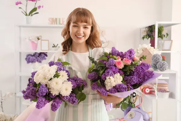 Çiçekçide leylaklarla dolu güzel buketler tutan kadın çiçekçi.