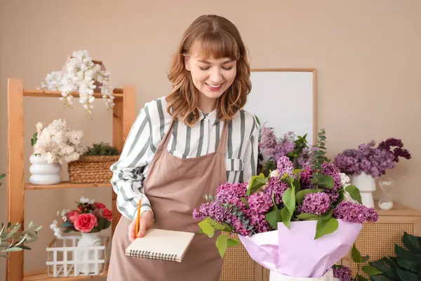 Çiçekçide çalışan defterli bir kadın çiçekçi.