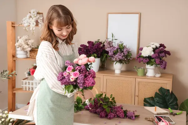 Çiçekçide elinde leylaklarla güzel bir buket tutan kadın çiçekçi.