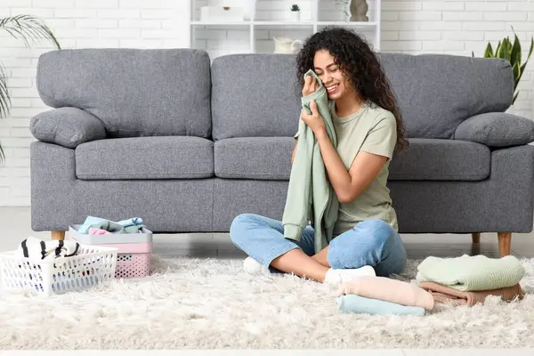 Güzel, genç, mutlu, Afro-Amerikan kadın. Temiz giysileri evde katlıyor.