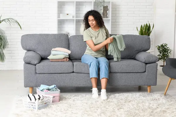 Güzel, genç, mutlu, Afro-Amerikan kadın. Temiz giysileri evde katlıyor.