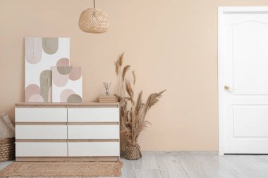 Çekmeceler, otlar, lambalar ve bej duvardaki güzel resimler.