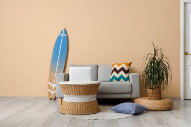 Sörf tahtası, rahat kanepe ve oturma odasında dizüstü bilgisayarı olan bir sehpa.