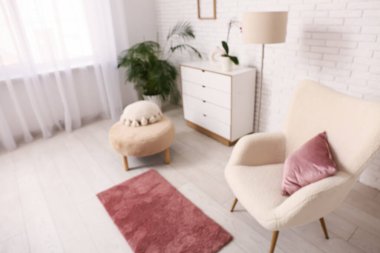 Oturma odasında rahat koltuk, halı ve yastıklı puf. Bulanık görünüm