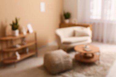 Rahat bir kanepe, büyük bir puf ve oturma odasında kitap ve çay olan bir kahve masası. Bulanık görünüm