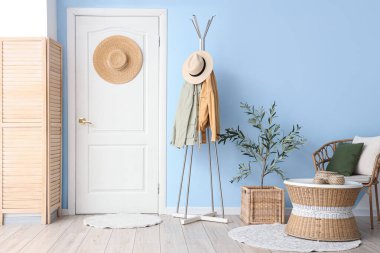 Rahat koltuğu, giysi rafı, kapısı ve zeytin ağacı olan güzel bir oturma odası.