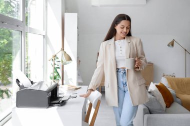 Ofisinde kahve ve matbaası olan genç bir iş kadını.