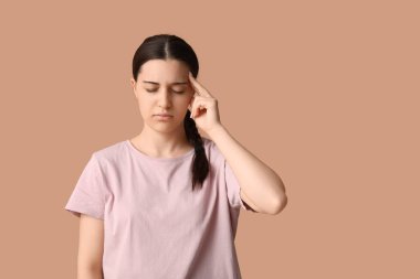 Bej arka planda baş ağrısı çeken güzel bir genç kadın.
