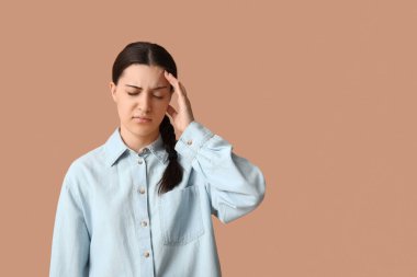 Bej arka planda baş ağrısı çeken güzel bir genç kadın.