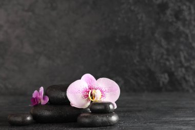 Koyu arkaplanda spa taşları ve orkide çiçekleri